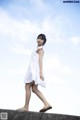 A woman in a white dress is walking on a concrete wall.