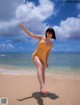 A woman in a yellow bathing suit standing on a beach.