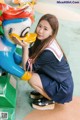 A woman in a sailor outfit is posing with a toy duck.