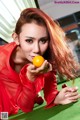 A woman in a red shirt holding a yellow ball.