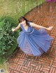 A woman in a blue dress is standing on a brick walkway.