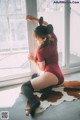 A woman in a red bodysuit sitting on a cowhide rug.