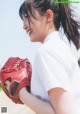 A woman in a white shirt holding a red baseball glove.