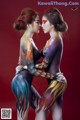 Two women with body paint hugging each other. 