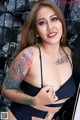 A woman with tattoos on her arms and chest posing for the camera.