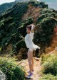 A woman in a white shirt and black shorts standing on a dirt road.