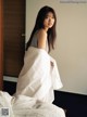 A woman standing on top of a bed holding a white sheet.