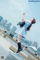 A woman in a blue dress is standing on a ledge.