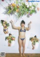 A woman in a bikini holding a bunch of flowers.