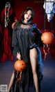 A woman in a black dress holding a pumpkin.