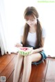 A woman sitting on the floor eating a slice of watermelon.