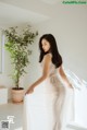 A woman in a white dress standing in a room.