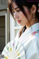 A woman in a white kimono holding a white fan.