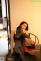 A woman sitting at a table with a pair of red shoes on it.