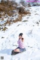 A woman sitting on a rock in the snow.