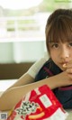 A young girl sitting at a table eating a bag of chips.