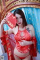 A woman in a red lingerie holding a red envelope.