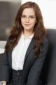 A woman in a business suit sitting on a chair.