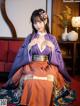 A woman in a purple and orange hanfu sitting on a red couch.