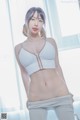 A woman in a white bra top and gray pants posing for a picture.
