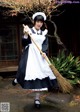 A woman dressed as a maid holding a broom.