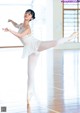 A young ballerina in a white leotard and pointe shoes in a dance studio.