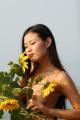 A naked woman standing next to a bunch of sunflowers.