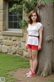 A young woman leaning against a tree in front of a house.