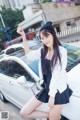 A woman posing in front of a white car.