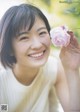 A woman holding a pink flower in her hand.