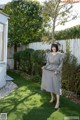 A woman standing in a yard next to a tree.