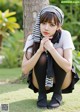 A young woman sitting on the grass with her legs crossed.