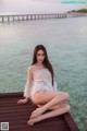 A woman sitting on a wooden dock by the water.